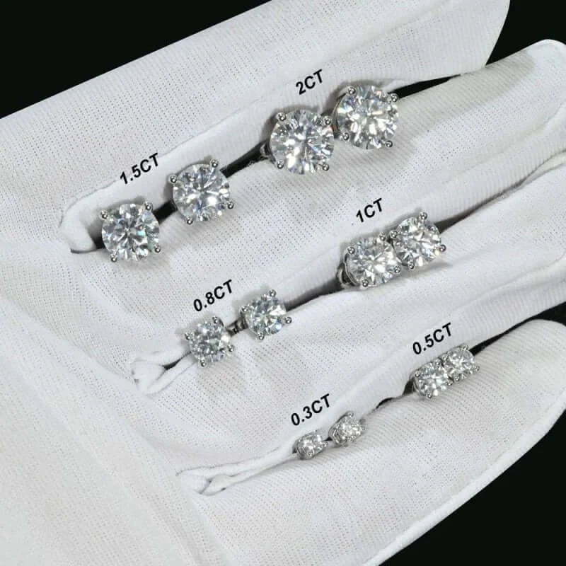Collection of various Moissanite stud earrings in different carat sizes displayed on white fabric.